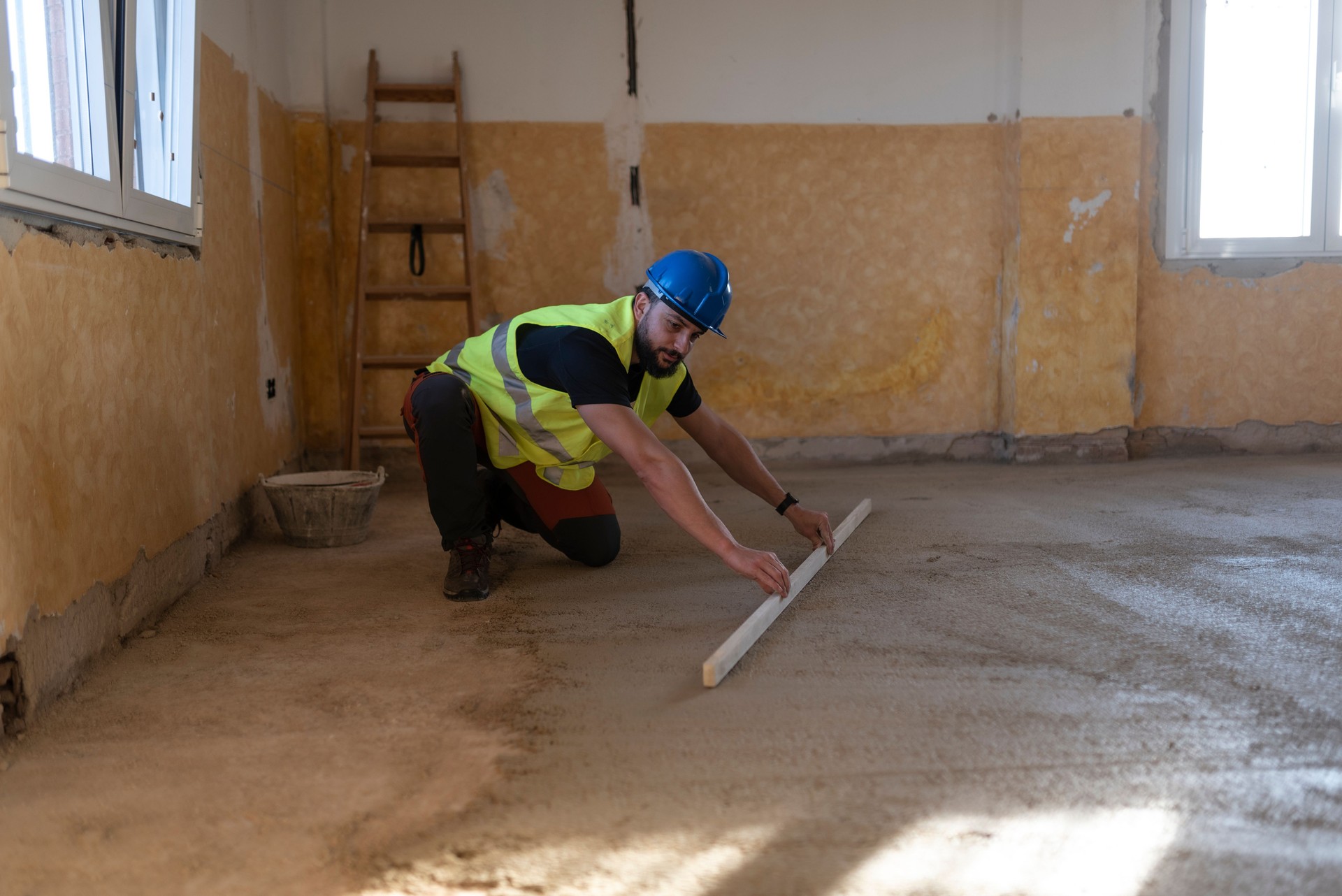 40-year-old construction worker renovating a house, leveling floor cement